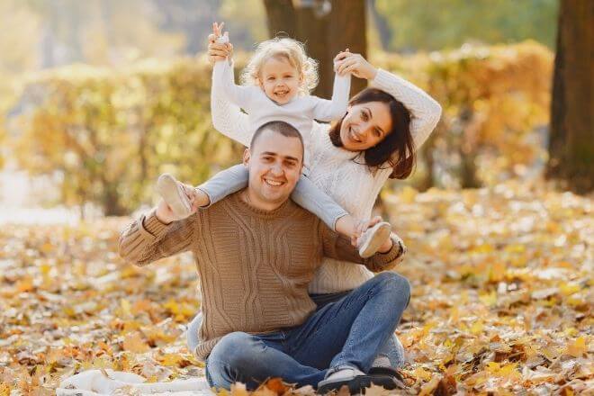 Vater, Mutter und Tochter sitzen auf dem Boden. Herbstliche Athmosphäre.